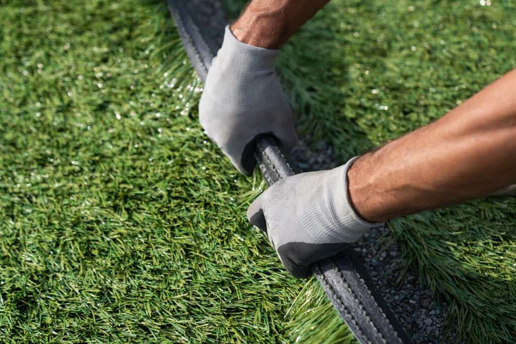 A person in gloves is trimming grass, highlighting lawn maintenance in Las Vegas, NV