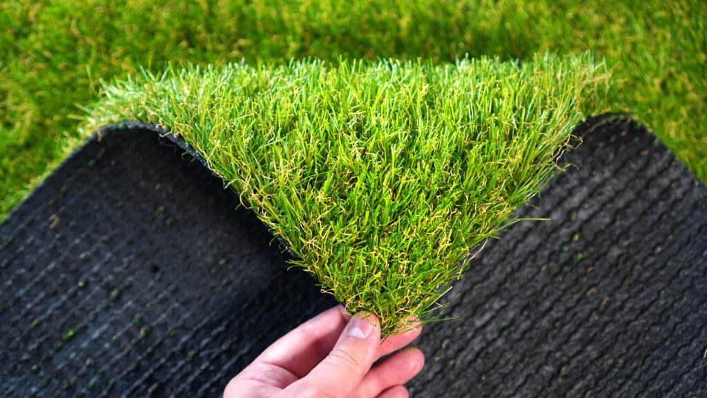 A person showcasing a piece of artificial grass from Artificial Grass Designs in Las Vegas, NV
